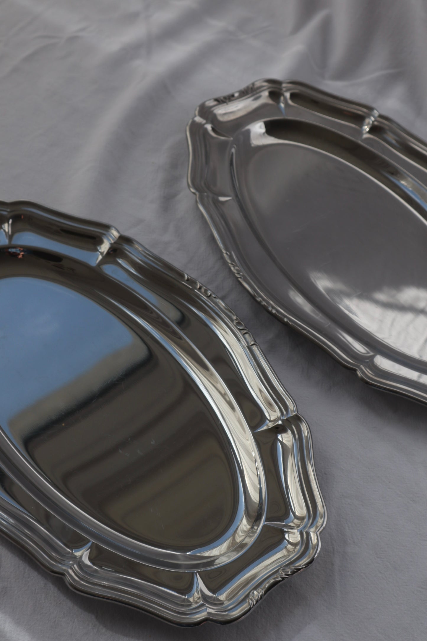 Pair of inox hosting platters with decorative edges